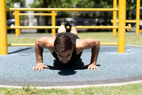 Fit male engaging in a push-up workout at an outdoor gym.