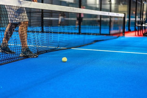 Cropped photo of a tennis ball next to the net while friends playing indoors