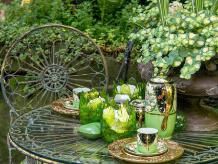 A decorated garden table with green tea service, glasses and plants in the background, borken,