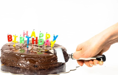 Female person cutting a homemade sacher chocolate cake with birthday candles