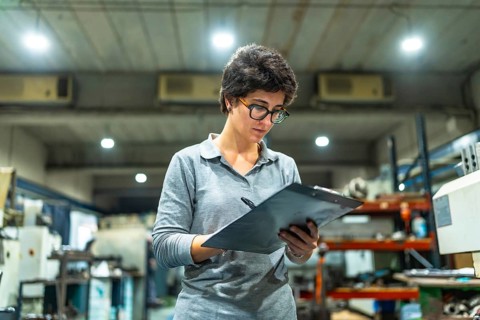 Frontal low angle view of a concentrated caucasian female manager writing while doing inventory in