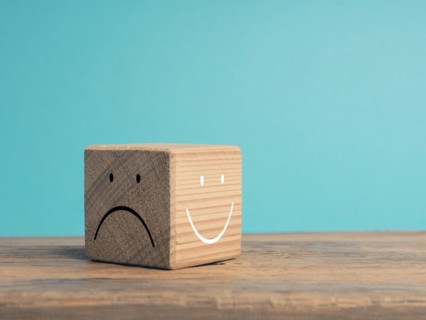A wooden cube with light and dark side, once with smiling face and with sad face, There is always