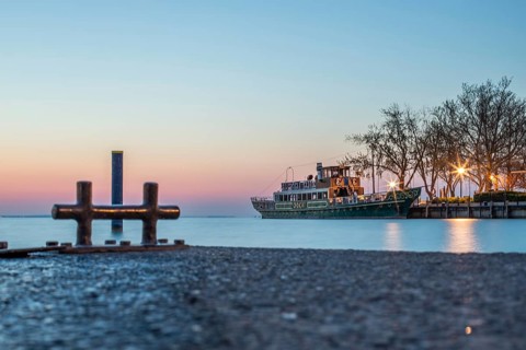 Sunrise on the shore and harbour of a lake in summer. Colourful sky with a wide view of the horiont