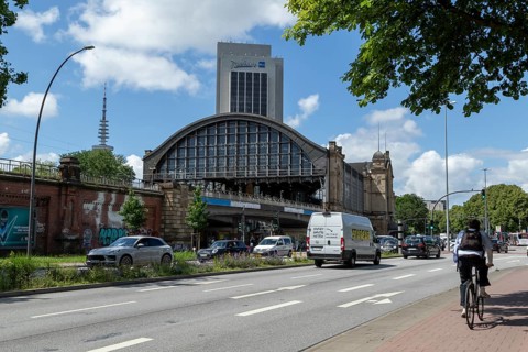 Traffic, cyclists and cars on the street at Dammtor railway station, behind them television tower