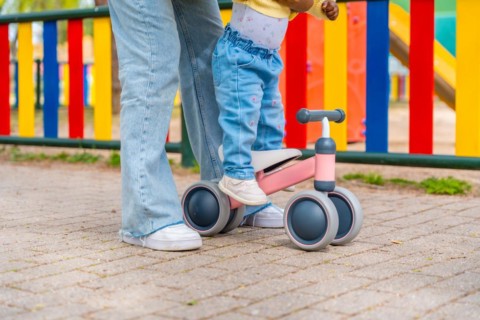 Lower section photo of an unrecognizable baby girl learning to rode a bike with her mother