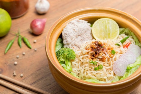 Hot and spicy noodle with pork and vegetables on the wood background