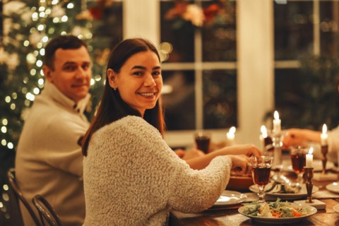 Happy young family couple smiling at camera while sitting at festive dinner table served for