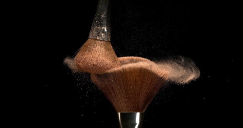 Make-up Brush spreading blush powder on black background