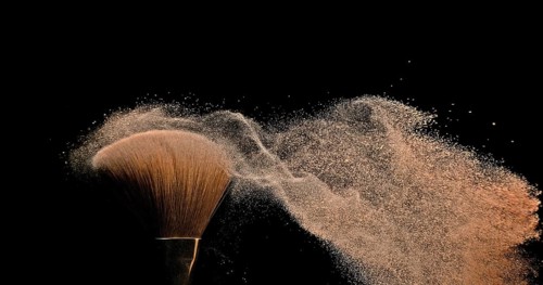 Make-up Brush spreading blush powder on black background