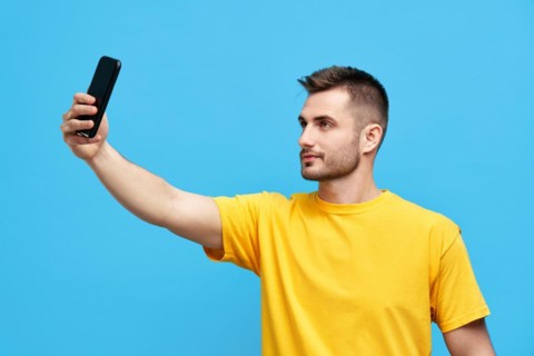 Handsome young man taking selfie over blue background. People concept