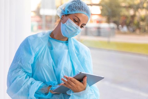 Female doctor protective wear looking clipboard