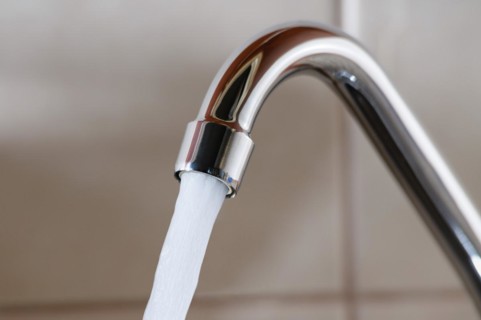 Horizontal image of a tap with water flowing strongly under high pressure