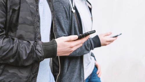 two unrecognizable antisocial mobile phone addicted male teenagers using smartphone, technology