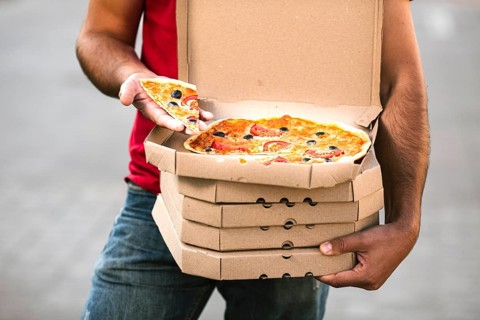 Close up delivery guy holding pizza slice