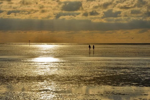 Evening atmosphere, sunset, Wadden Sea, two people walking between Neuwerk Island and