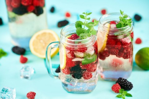 Fresh berries cocktail in glass jar. Fresh summer cocktail with mix of berries, lemon and mint on