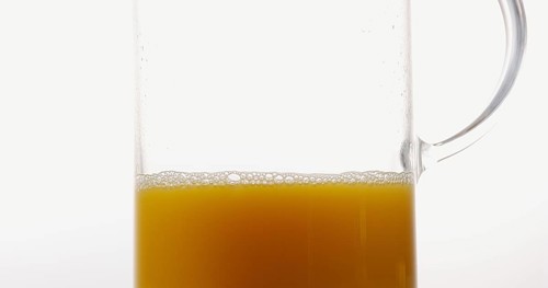 Orange Juice being poured into Glass against White Background