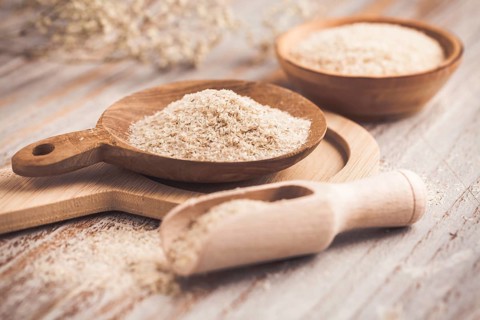 Heap of psyllium (Plantago ovata) husk in wooden bowl on wooden table table. Psyllium husk also