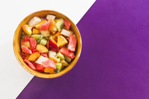 Bowl fruit salad white purple background
