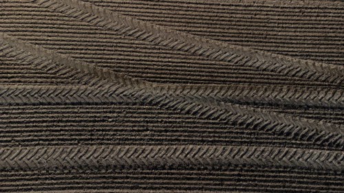 Tractor tyre tracks form an interesting pattern on a freshly cultivated field without vegetation,