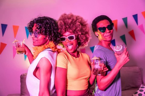 Happy diverse friends laughing partying and drinking alcohol at night with colorful neon light