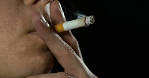 Woman smoking a Cigarette against Black Background