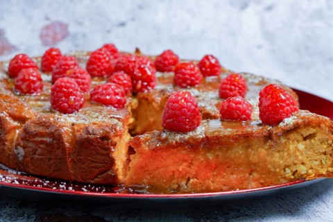 Homemade sweet potato, cake with raspberries and coconut flakes on a red plate