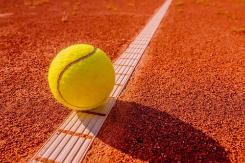 Yellow tennisball on the line at a clay court