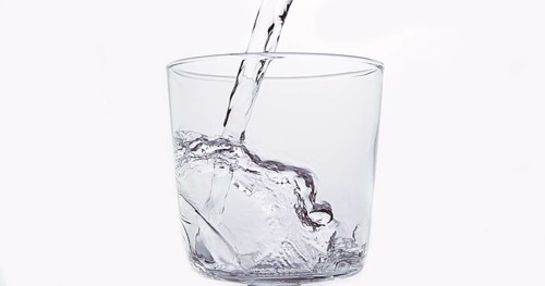 Water being poured into Glass against White Background