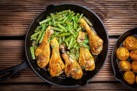 Chicken legs in pan with potatoes, green beans and salad