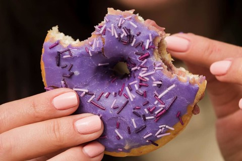 Close up woman eating purple donut