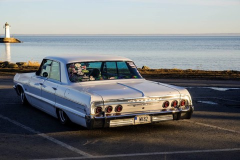 American classic car, Chevrolet Impala from 1964, behind the lake Vättern and the lighthouse of