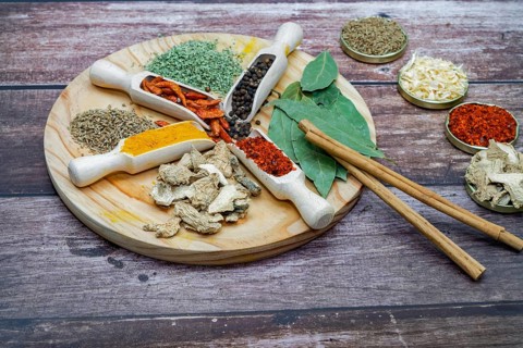 Different types of spices in wooden spoons on a wooden disk ginger, cayenne, pepper, cinnamon,