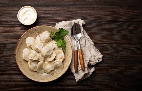 Pelmeni, traditional dish of Russian cuisine, boiled dumplings with minced meat filling on plate