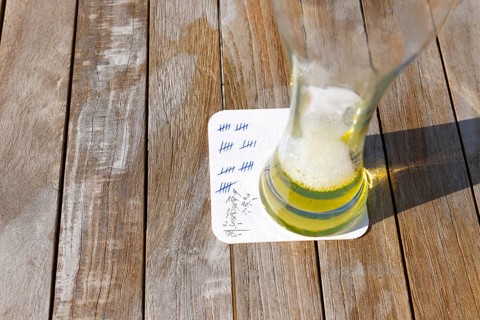 Empty beer glass on a beer mat with strokes