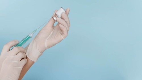 Hand with gloves holding syringe with vaccine copy space