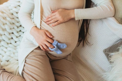 Maternity and pregnancy concept. Cropped photo of pregnant woman holding pair of cute blue baby