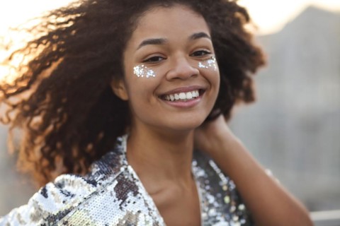 Close up portrait of overjoyed charming african american woman with curly hair and glitter on