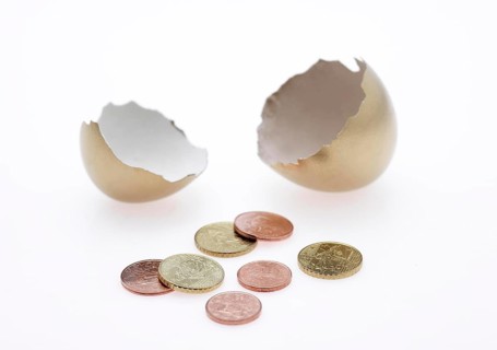 Gold Chicken Egg with Euro Coins against White Background
