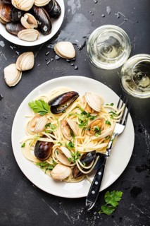 Spaghetti vongole, Italian seafood pasta with clams and mussels, in plate with herbs and two