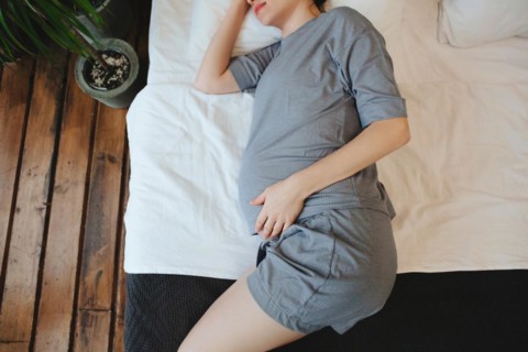 View from above of pregnant woman relaxing resting on couch at home, expectant mother lying on sofa