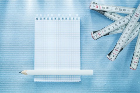 Checked notebook pencil measuring tape construction concept