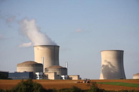 A farmer ploughs his field in front of the nuclear power plant in Cattenom, background blue sky