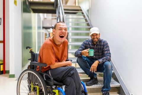 Man with cerebral palsy having fun with teamwork in coworking during a coffee break indoors