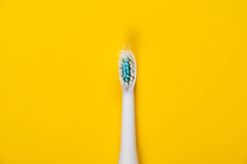 Used brush head of an electric toothbrush in front of a monochrome background
