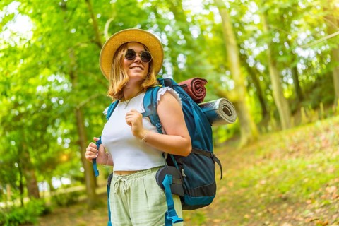 Beauty cheerful caucasian female backpacker enjoying nature while trekking in the forest