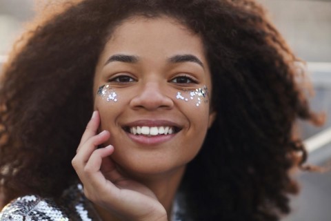 Close up portrait of overjoyed charming african american woman with curly hair and glitter on