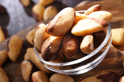 Composition with a bowl of shelled brazil nuts. Delicacies