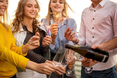 Group of partying friends with flutes with champagne and bengal fire having fun on the party on the