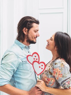 Couple holding paper hearts wooden stick
